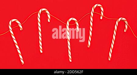Muster von Weihnachtsbonbon Stock auf brauner Schnur auf hellrotem Hintergrund. Hintergrundkonzept Für Feiertage. Flachbanner. Stockfoto