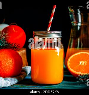 Weihnachtscocktail. Orange frisch im Glas mit Tube steht auf einem Holztisch neben Weihnachtsspielzeug Stockfoto
