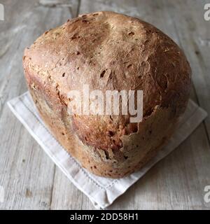 Hausgemachtes Vollkorn Roggen Weizen Sauerteig Bio Brot Laib auf Leinen Serviette auf Holz Hintergrund Stockfoto