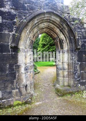 Stein gewölbte Tür in Whalley Abbey , Lancashire , Großbritannien in 2020 - in 1296 die Mönche von Stanlow Point, Cheshire zog nach Norden Whalley, Lancashire, wo sie ein neues Kloster neben dem Fluss Calder gebaut. An der Stelle befand sich bereits eine Kapelle, die von Peter von Chester, dem Rektor von Whalley, errichtet wurde, und das Gebäude aus dem 13. Jahrhundert wurde in das neue Kloster integriert. Der Grundstein für die neue Abteikirche wurde im Juni 1296 von Henry de Lacy, dem 10. Baron von Halton, gelegt. Stockfoto