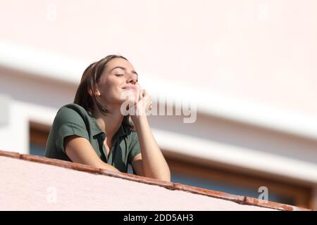 Glückliche Frau atmen tiefe frische Luft vom Balkon in der Wohnung Ein sonniger Tag Stockfoto