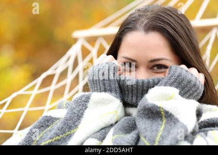 Glückliche Frau spähen vom Pullover auf einer Hängematte im Herbst In einem Wald Stockfoto