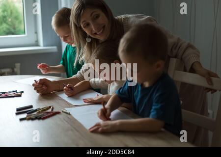 Mama mit drei Kindern zeichnet. Zeichnen Sie mit Filzstiften. Stockfoto