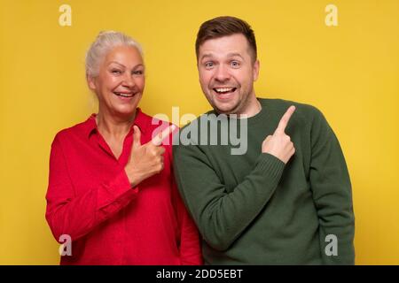 Reife Mutter und Sohn zeigen mit Hand und Finger nach oben Zur Seite mit fröhlichem Ausdruck im Gesicht Stockfoto