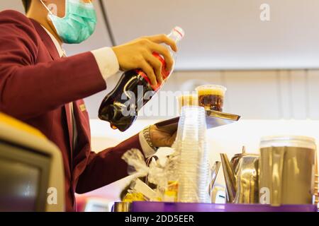 Flugbegleiter in Gesichtsmaske dient Passagieren ein weiches während covid-19. Stockfoto