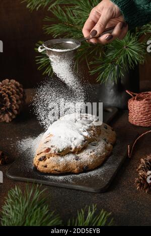 Frau Puderzucker Weihnachtsstollen auf braunem Hintergrund. Weihnachtsgebäck Dessert. Vertikales Format. Nahaufnahme. Stockfoto