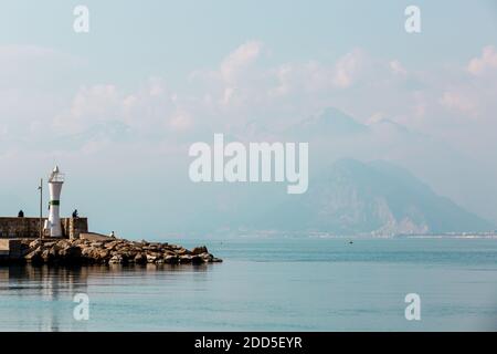 Antalya, Türkei - 22. Februar 2019: Menschen sitzen in der Nähe des Leuchtturms im Hafen in der Altstadt von Kaleici in Antalya. Stockfoto