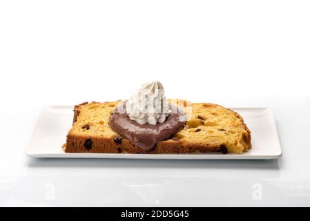 Scheibe Panettone mit Schokolade und Milchcreme auf der weißen rechteckigen Platte, typisch italienisches Dessert für Weihnachten aus Mailand, isoliert auf weiß Stockfoto