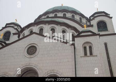 Details des Heiligen Sava-Tempels (Hram Svetog Save, auf Serbisch), Fenster und Kuppel mit goldenem Kreuz auf der Oberseite, mächtige weiße Wände. Stockfoto