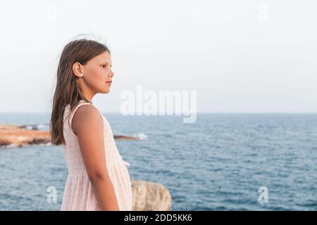 Kleines Mädchen in weißem Kleid mit der Hauptrolle am Meer, Außenportrait Stockfoto