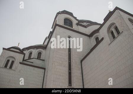 Details des Heiligen Sava-Tempels (Hram Svetog Save, auf Serbisch), Fenster und Kuppel mit goldenem Kreuz auf der Oberseite, mächtige weiße Wände. Stockfoto