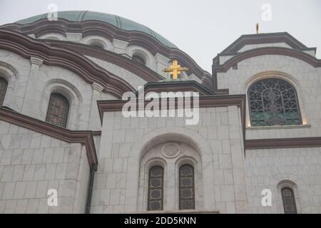 Details des Heiligen Sava-Tempels (Hram Svetog Save, auf Serbisch), Fenster und Kuppel mit goldenem Kreuz auf der Oberseite, mächtige weiße Wände. Stockfoto