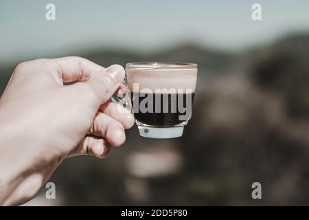 Behandeln Sie heißen Americano Kaffee in einem Glas mit Sonnenlicht in der Morgenzeit und natürlichen Hintergrund platziert. Stockfoto