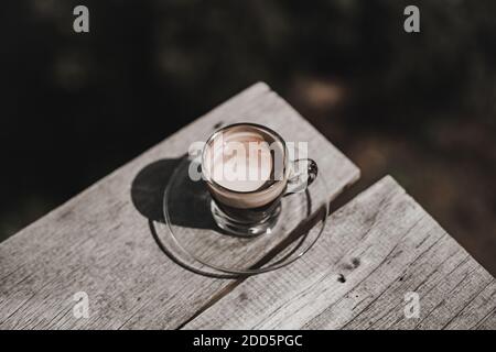Topview von Hot Americano Kaffee in einem Glas auf einem Holztisch mit Sonnenlicht in der Morgenzeit platziert. Stockfoto