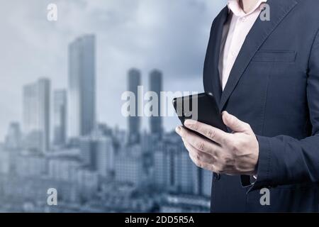 Online-Geschäft. Geschäftsmann hält Handy mit Zeichen das globale Netzwerk. Mann mit Smartphone auf verschwommene Stadt Hintergrund. Mann in Stockfoto