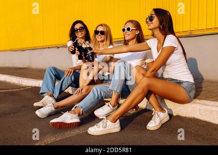 Glückliche junge Menschen klirren Glasflaschen mit Getränken feiern Ausgaben Zeit zusammen vor gelbem Wandhintergrund im Sommer Stockfoto