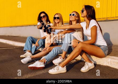 Glückliche junge Menschen klirren Glasflaschen mit Getränken feiern Ausgaben Zeit zusammen vor gelbem Wandhintergrund im Sommer Stockfoto