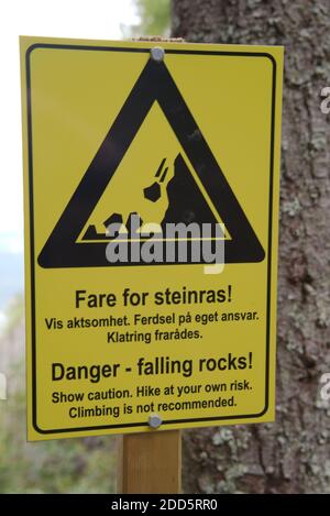 Gelbes Schild warnt Wanderer vor den Gefahren fallender Felsen in der Gegend. In Norwegisch und Englisch. . Hochwertige Fotos Stockfoto