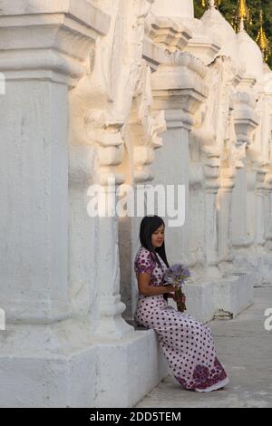 Junge Frau, die im Februar in der Kuthodaw Pagode, Mandalay, Myanmar (Burma), Asien, Blumen hält Stockfoto