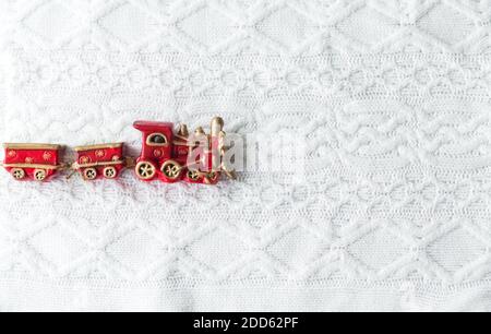 Spielzeug-Dampflokomotive in roter Farbe auf einem weißen gestrickten Hintergrund Stockfoto