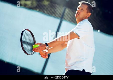 Junger professioneller Tennisspieler, der einen Service leistet Stockfoto