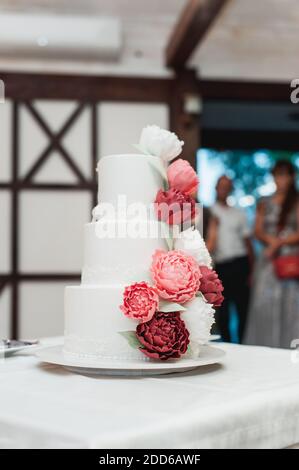 Schöne Hochzeitstorte mit roten Rosen bei der Hochzeit dekoriert Zeremonie Stockfoto