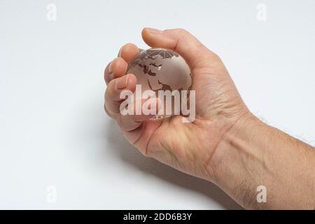 Eine männliche Hand hält den Erdglobus aus Glas in der Hand Stockfoto