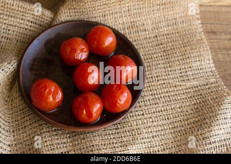 Eingelegte Kirschtomaten auf einem Holztisch im rustikalen Stil. Einkanterkonzept Stockfoto