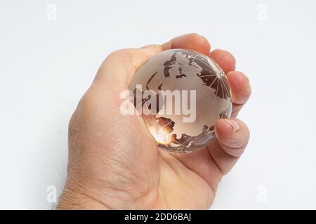 Eine männliche Hand hält den Erdglobus aus Glas in der Hand Stockfoto