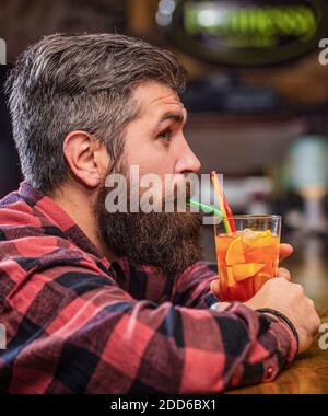 Tropischer alkoholischer frischer Cocktail. Barkeeper im Pub oder Restaurant. Bartmann Cocktail. Portrait Mann, trinkt Orangensaft. Bärtiger Mann trinkt Cocktails Stockfoto
