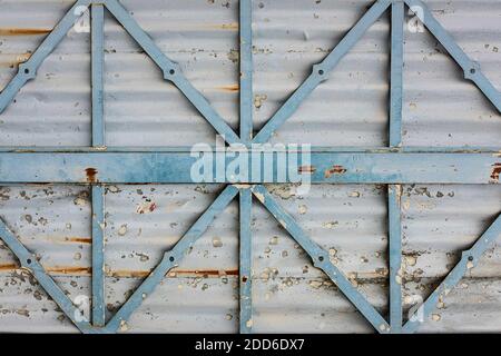 Textur einer grauen, verrosteten Metalloberfläche mit hellblauen Metallstreben, verwitterte, abblätternde Farbe Stockfoto