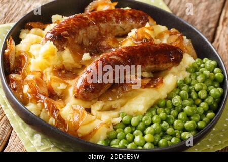 Irish Bangers and Mash ist ein Gericht, bestehend aus Würstchen mit Kartoffelpüree und Zwiebelsoße in der Nähe in der Platte auf dem Tisch serviert. Horizontal Stockfoto