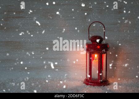 Weihnachtslaterne und fallender Schnee auf Holzwand mit Kopierraum. Rote Laterne und Schneeflocken auf Vintage Holz Hintergrund. Verschneite Szene mit leuchtendem lan Stockfoto