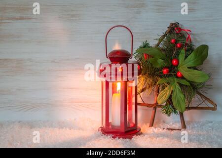 Weihnachtsbaum mit Beeren, brennende rote Kerze in Laterne Holzhintergrund für Kopieplatz. Weihnachtliche Dekoration Stockfoto