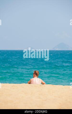 Tourist sitzt auf schönen weißen Sandy Nha Trang Strand, Vietnam, Südostasien Stockfoto