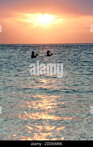 Fischer Angeln bei Sonnenuntergang im Meer am Sengiggi Strand, gegen die Sonne silhouetted, Lombok, Indonesien, Asien Stockfoto