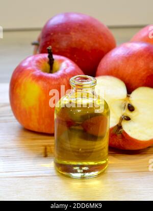 Apfelessig in Glasflasche und frische Äpfel auf Holzhintergrund Stockfoto