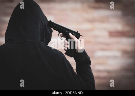 Ein Mann begeht Selbstmord mit einer Pistole, um sich selbst zu töten. Junger Mann zeigt eine Waffe auf seinen Kopf. Suicide-Konzept. Stockfoto