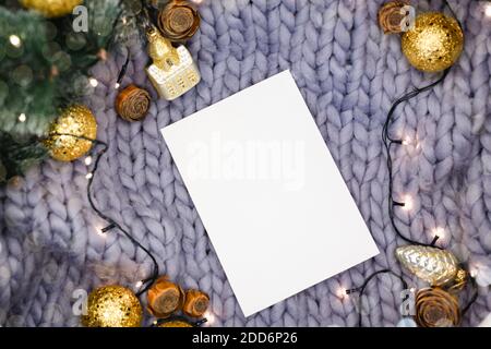 Weißes Blatt Papier auf grauem gestricktem Hintergrund zwischen Neujahrsdekorationen, flaches Lay Stockfoto