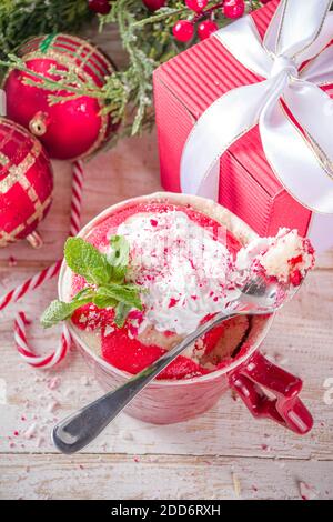 Zuckerrohr Pfefferminz-Mugcake. Einfaches Weihnachtsfrühstück, Snack-Idee Rezept, weiß und rot gewirbelter Biskuitkuchen in festlichen Tassen mit Schlagsahne und Stockfoto