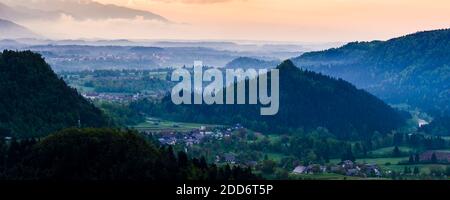 Typische slowenische Landschaft. Blick auf den nebligen Sonnenaufgang vom Osojnica-Hügel am Bleder See in Richtung Radovljica, Region Gorenjska, Slowenien, Europa Stockfoto