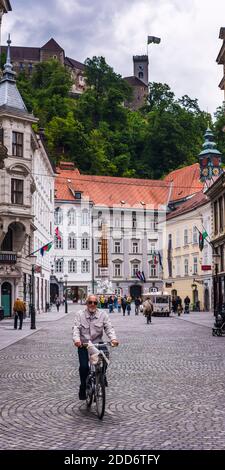 Person Radfahren in Ljubljana mit Burg Ljubljana im Hintergrund, Slowenien, Europa Stockfoto