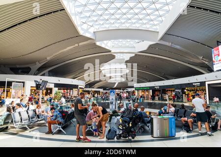 Innenraum des 2. Stockwerks des Abflugbereichs des Flughafens Leonardo da Vinci - Fiumicino Rom, Personen, die in einem Sitzbereich sitzen, der von Geschäften umgeben ist. Stockfoto