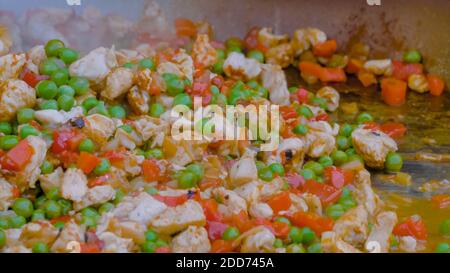 Prozess des Kochens von Fleischstücken, Paprika, Erbsen in riesigen Wok - close up Stockfoto