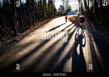 Fahrradfahrer werfen lange Schatten an einem Spätherbst (November) Tag, East Montpelier, VT, New England, USA. Stockfoto