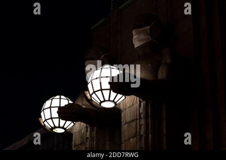 Zwei Statuen, die kugelförmige Lampen halten und Gesichtsmasken tragen Der Eingang zum Hauptbahnhof von Helsinki Stockfoto