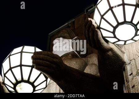 Zwei Statuen, die kugelförmige Lampen halten und Gesichtsmasken tragen Der Eingang zum Hauptbahnhof von Helsinki Stockfoto