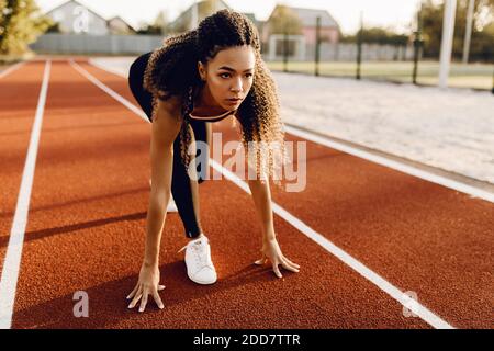 Junge sportliche Frau Läuferin am Stadion Startlinie immer bereit für Rennen, Sportkonzept Stockfoto