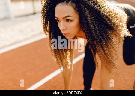 Junge sportliche afroamerikanische Läufer am Stadion Startlinie immer bereit für Rennen, Sport-Konzept Stockfoto