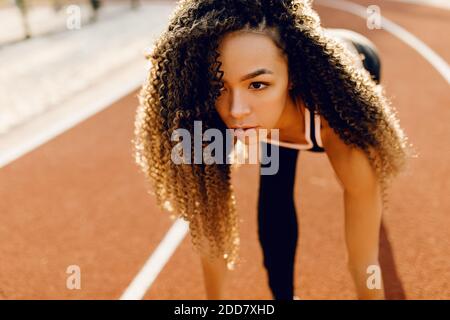 Junge sportliche afroamerikanische Läufer am Stadion Startlinie immer bereit für Rennen, Sport-Konzept Stockfoto